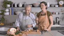an older man and a younger woman are preparing food in a kitchen with the number 52 on the corner