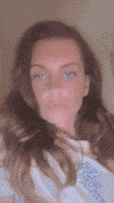 a woman with long hair and blue eyes is wearing a white shirt