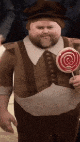 a man in a hat is holding a lollipop