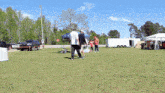 a group of people standing in a grassy field with a white trailer in the background