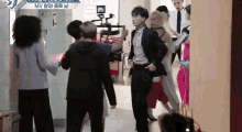 a group of people are standing in a hallway with a sign that says black suit