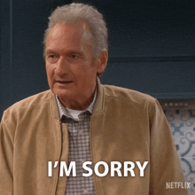 a man in a tan jacket says i 'm sorry in front of a netflix logo
