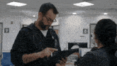 a doctor is talking to a nurse in a hospital while holding a tablet .