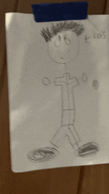 a child 's drawing of a stick figure is taped to a wooden surface