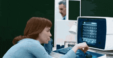 a woman playing a game on a computer with a man behind her