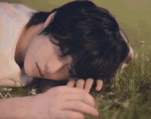 a person laying down in the grass with their hand on their face
