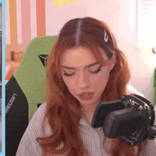 a woman with red hair is sitting in front of a microphone in a room .