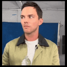 a man in a green jacket holds a water bottle
