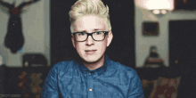a man wearing glasses and a blue shirt has the word troylered on the bottom
