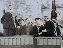 a group of men standing on a balcony with a flag in the background .