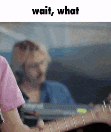 a man playing a guitar with the words wait what written above him