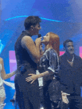 a man is singing into a microphone while a woman stands behind him