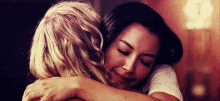 two women are hugging each other with their eyes closed and smiling .