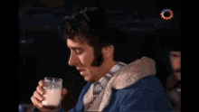 a person is holding a glass of milk and a pencil in their hand .
