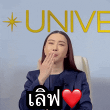 a woman blowing a kiss in front of a wall that says unive