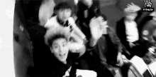 a black and white photo of a group of people sitting around a table .