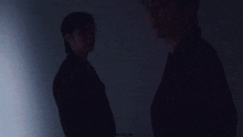 a couple of men are standing next to each other in a dark room .