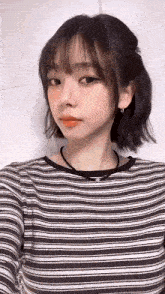 a girl with short hair is wearing a striped shirt and earrings .