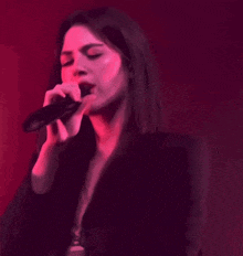a woman singing into a microphone in a red light
