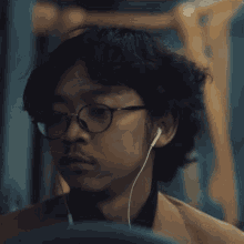 a man wearing glasses and ear buds looks serious