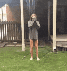 a woman in a sweater and shorts is standing in front of a fence .