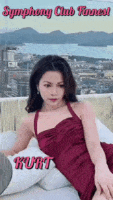 a woman in a red dress is laying on a couch with the name kurt on the bottom .