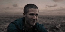 a man is sitting in the middle of a field looking at the camera .