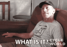 a man sitting on a couch with the words what is it cycle world written on the bottom