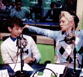 two men are sitting in front of microphones and one of them is pointing at another