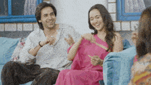 a man and woman sit on a blue couch laughing