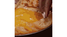 a close up of a person dipping a piece of food into a bowl of food .