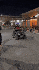 a group of people riding an atv in a parking lot at night