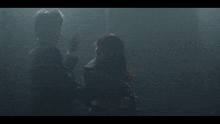 a man is holding another man 's head in a dark room
