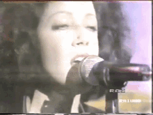 a close up of a woman singing into a microphone on a television screen .