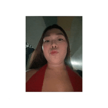 a woman in a red top is making a funny face while looking at the camera .