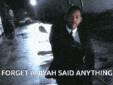 a man in a suit and tie is walking down a street with the words " forget aniyah said anything " above him