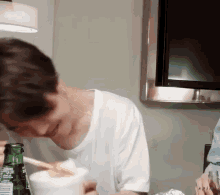 a man in a white shirt is drinking from a bottle that says ' sprite ' on it