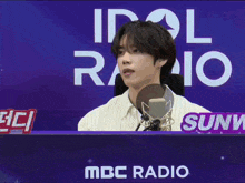 a young man sitting in front of a mbc radio sign