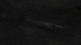 a large black robot is sitting on a rocky hillside