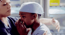 two nurses are hugging each other in a hospital room and one of them is crying .