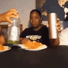 a person wearing a shirt that says go getter is sitting at a table with plates of food