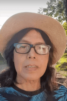a woman wearing a hat and glasses is looking at the camera