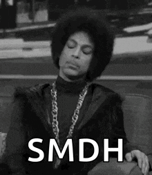 a black and white photo of prince sitting on a couch with the words smdh written on it .