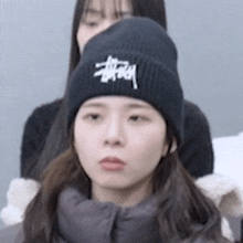 a woman wearing a black hat with the word stussy on it