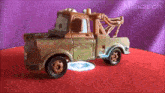 a toy tow mater truck is on a red surface