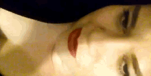 a close up of a woman 's face with red lips and a hat on .