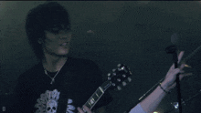 a man playing a guitar and singing into a microphone with the letter d in the corner