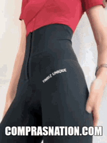 a woman is wearing a red shirt and black pants with the words comprasnation.com on the bottom .