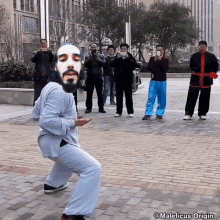 a man with a beard is dancing in front of a group of people who are taking pictures