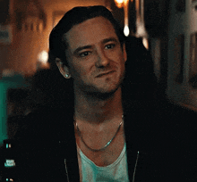a close up of a man wearing a black jacket and a chain .